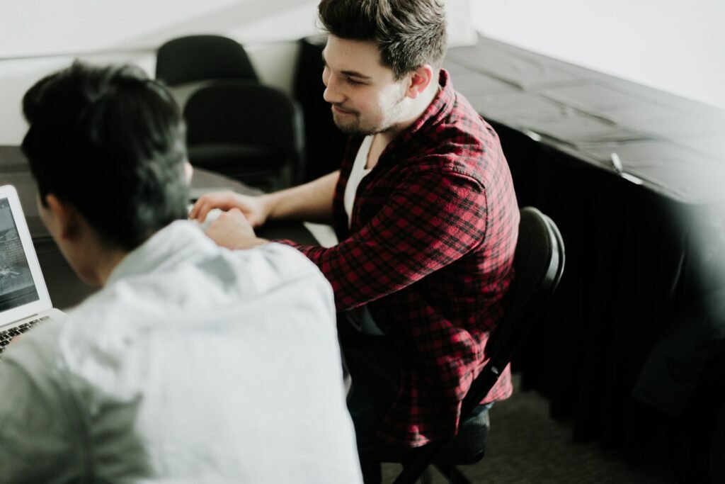 A man sitting at a desk shaking hands with another man
